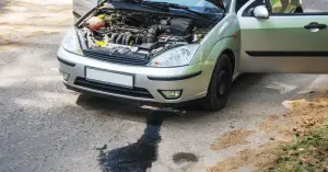 car on the side of the road with oil leak on the right side of engine