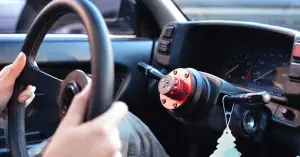 person removing car steering wheel from column
