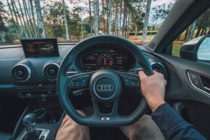 man holding Audi steering wheel with right hand