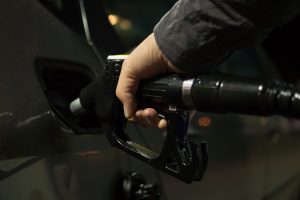 man uses fuel pump to put gas in gas tank
