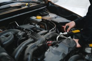 person working on car engine under hood