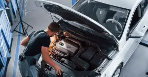 mechanic looking under car hood to examine engine