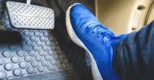 blue shoe pressing against gas pedal accelerator