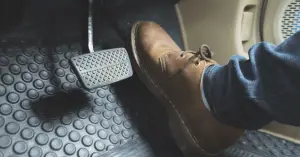 close up leather shoe pressing car accelerator pedal 