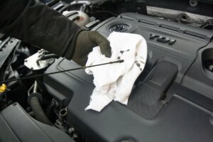mechanic removing dipstick to change oil in car